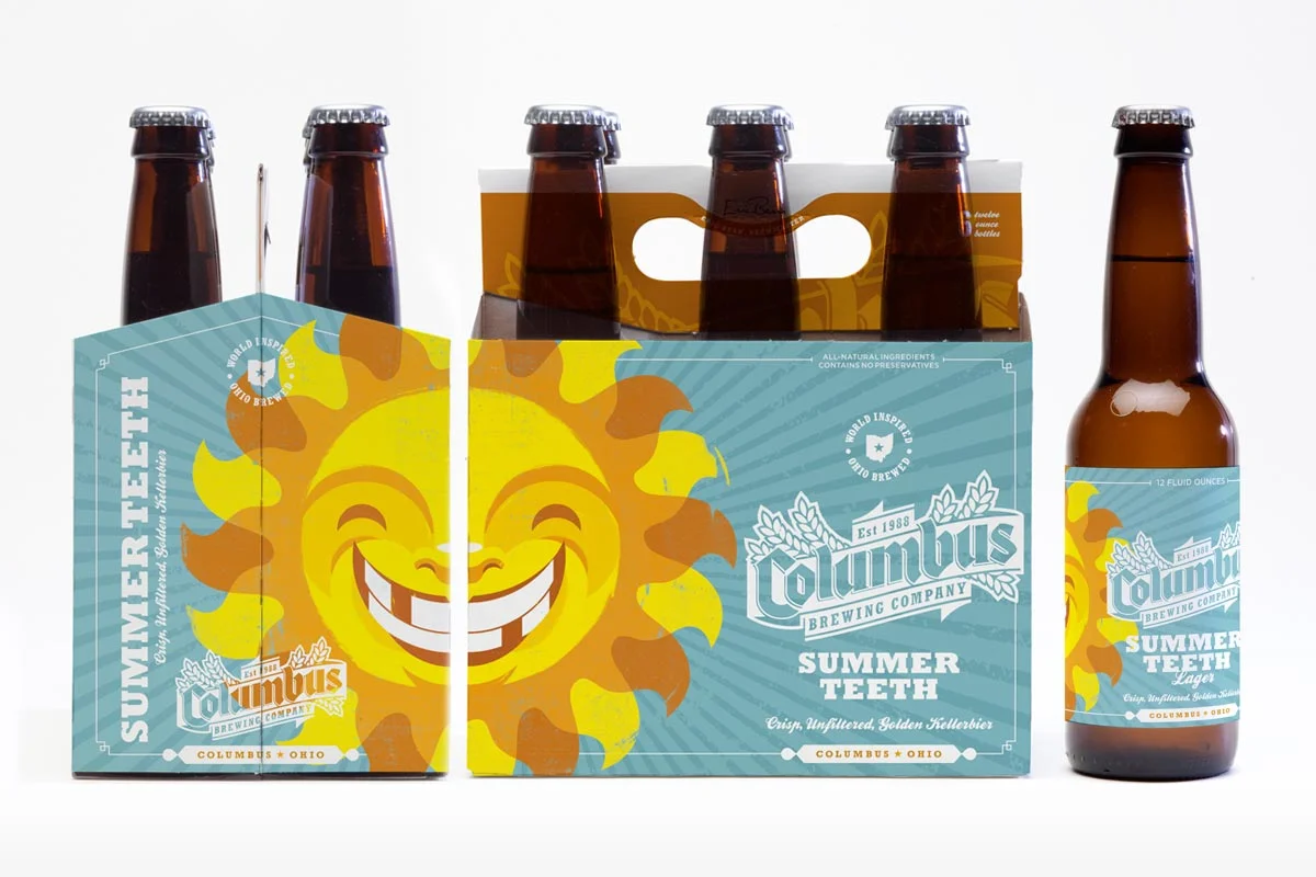 Six bottles of Columbus Brewing Company's Summer Teeth lager, with five bottles in a six-pack carrier and one bottle outside the carrier. The packaging features a smiling, cartoonish sun with a face, in bright yellow and orange colors, and the labels