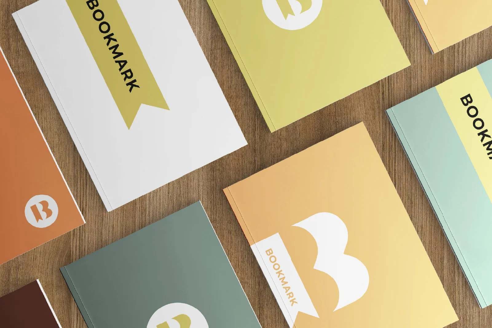 Multiple colorful journals or notebooks with bookmarks on a wooden surface, each labeled 'BOOKMARK' on the cover.