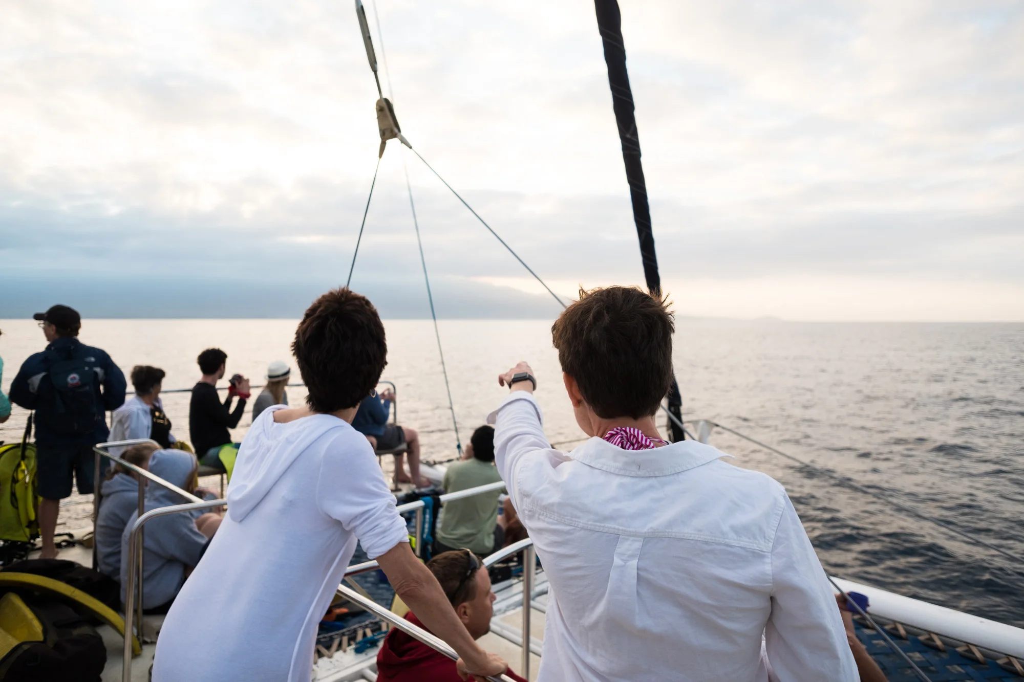 People whale watching on a boat sailing on open water during cloudy weather Maui.