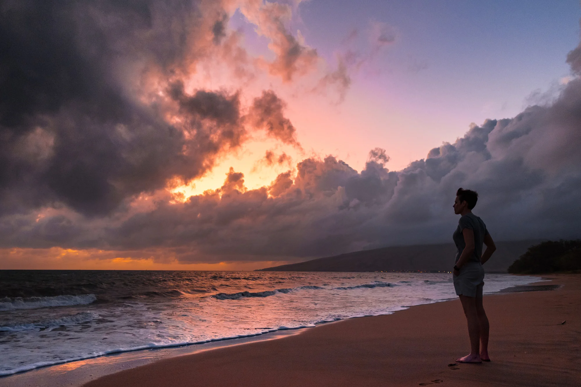 A woman tanding on a beach during sunset, in Maui