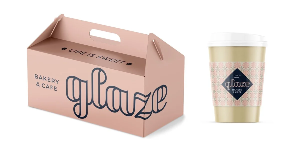 A pink bakery box with the words "glaze" and "bakery & cafe" printed on it, alongside a to-go coffee cup with a patterned pink sleeve and a blue diamond-shaped logo.