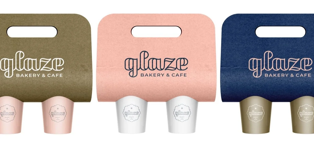 Three paper bakery and cafe bags in olive green, pink, and navy blue with coffee cups beneath each, displaying the "glaze" logo.