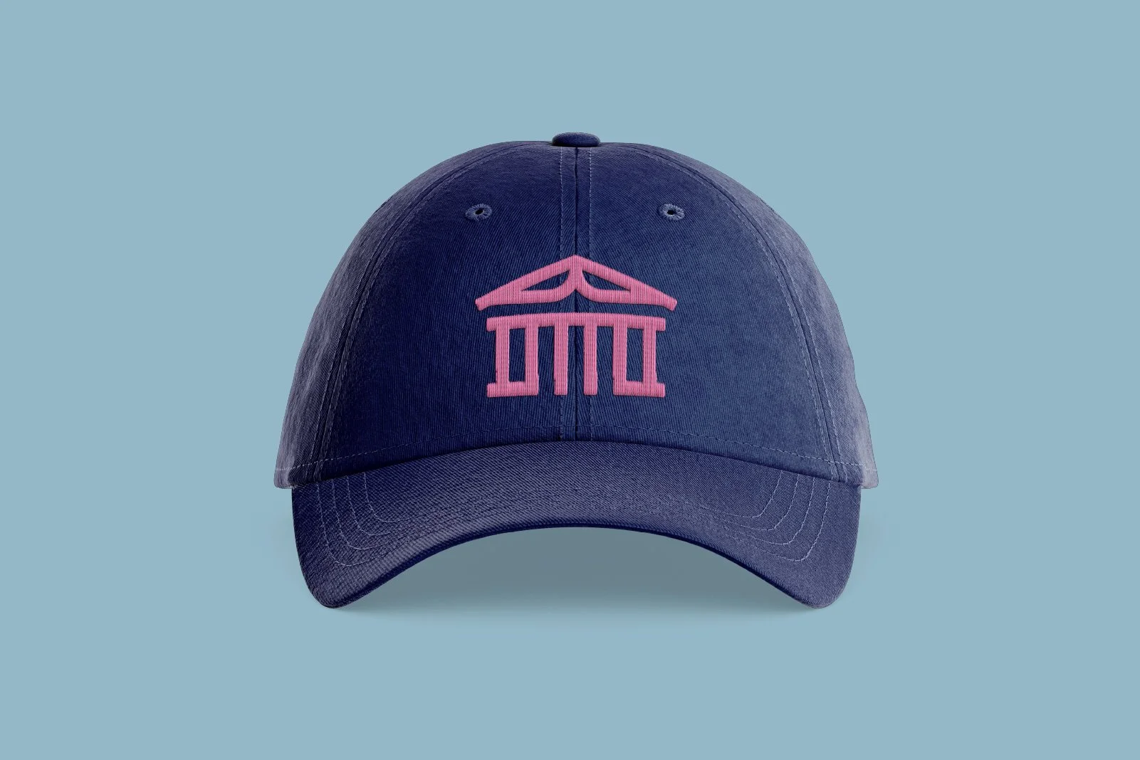 A navy blue baseball cap with pink embroidery of a Greek temple on the front, against a light blue background.