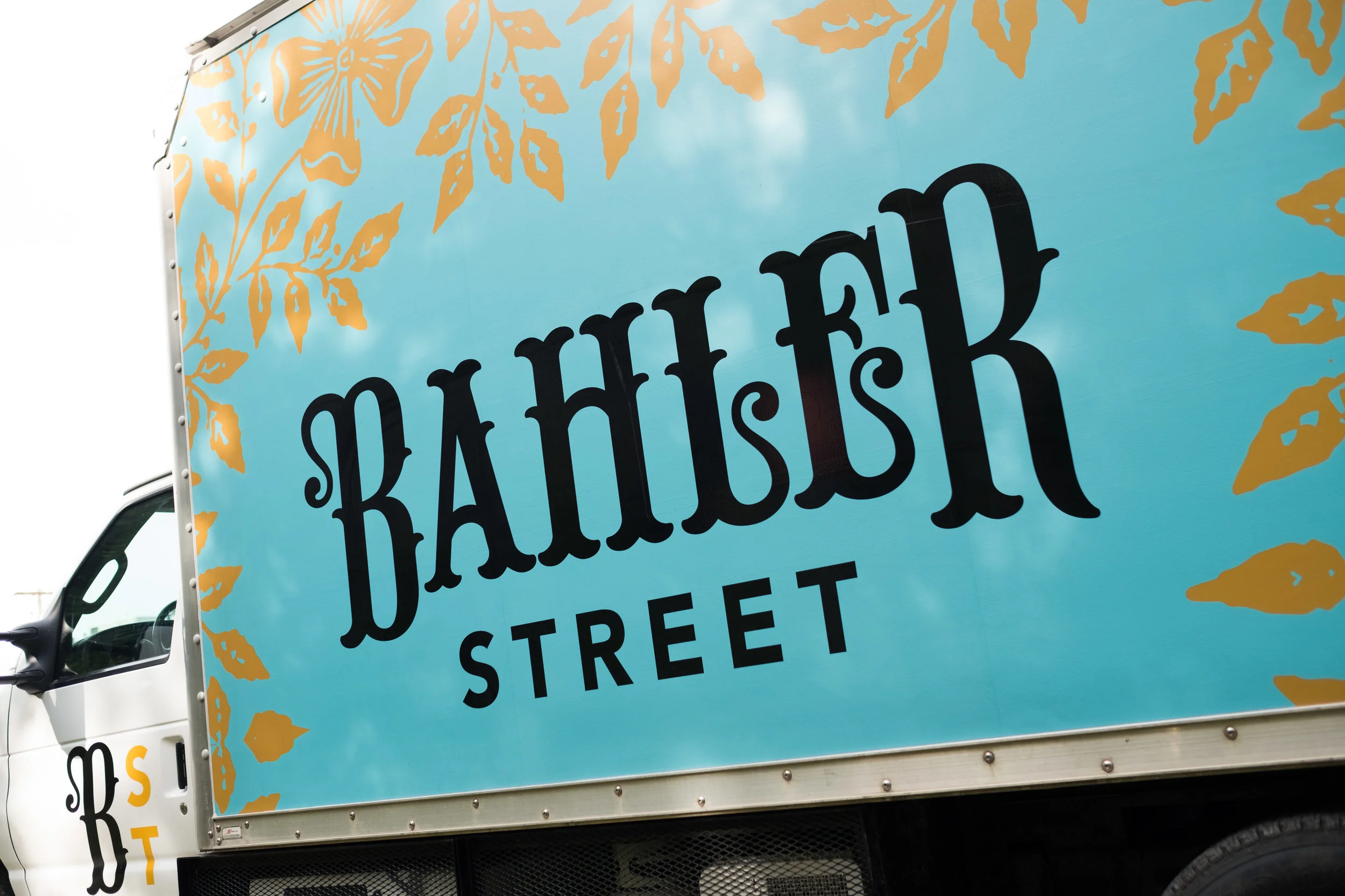 A truck with a large sign reading 'Bangkok Street' on a teal background, decorated with gold floral patterns.