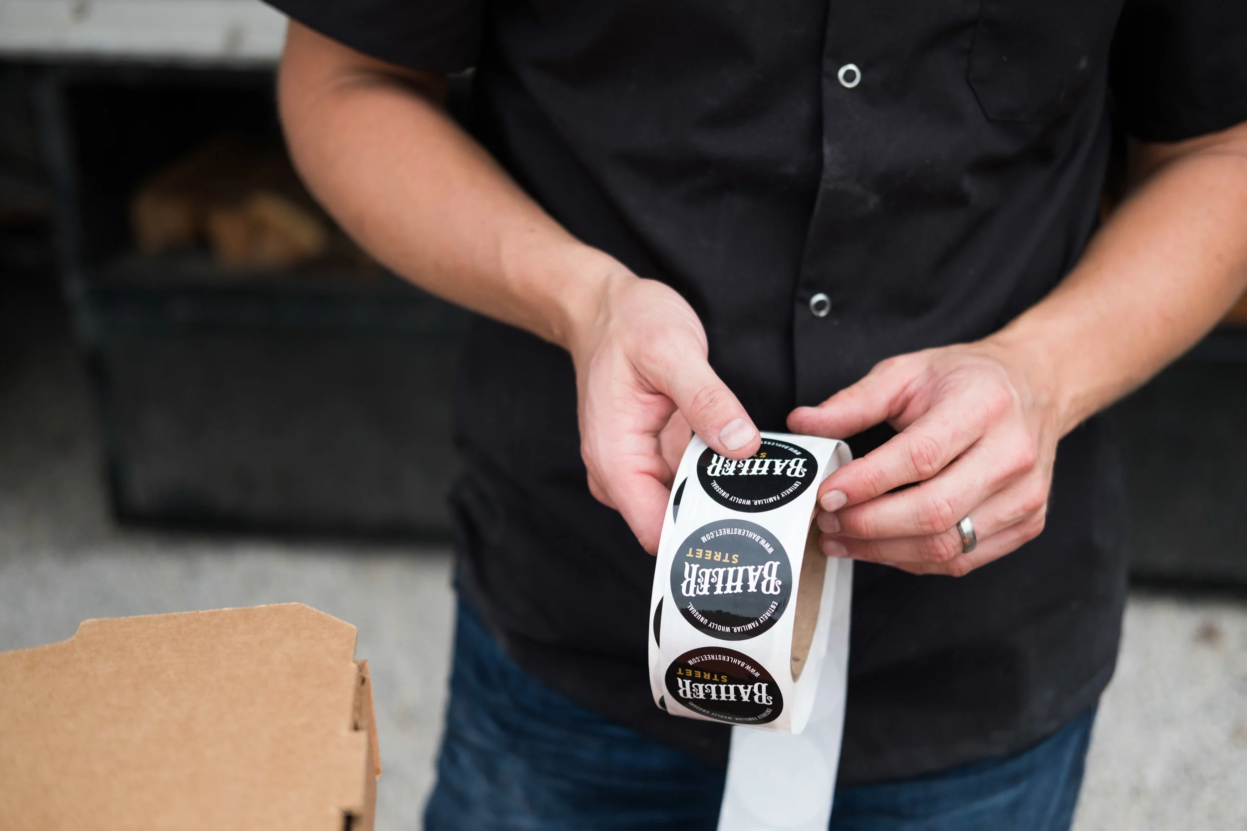 Person applying Bairsh BBQ sticker to a roll of decals.