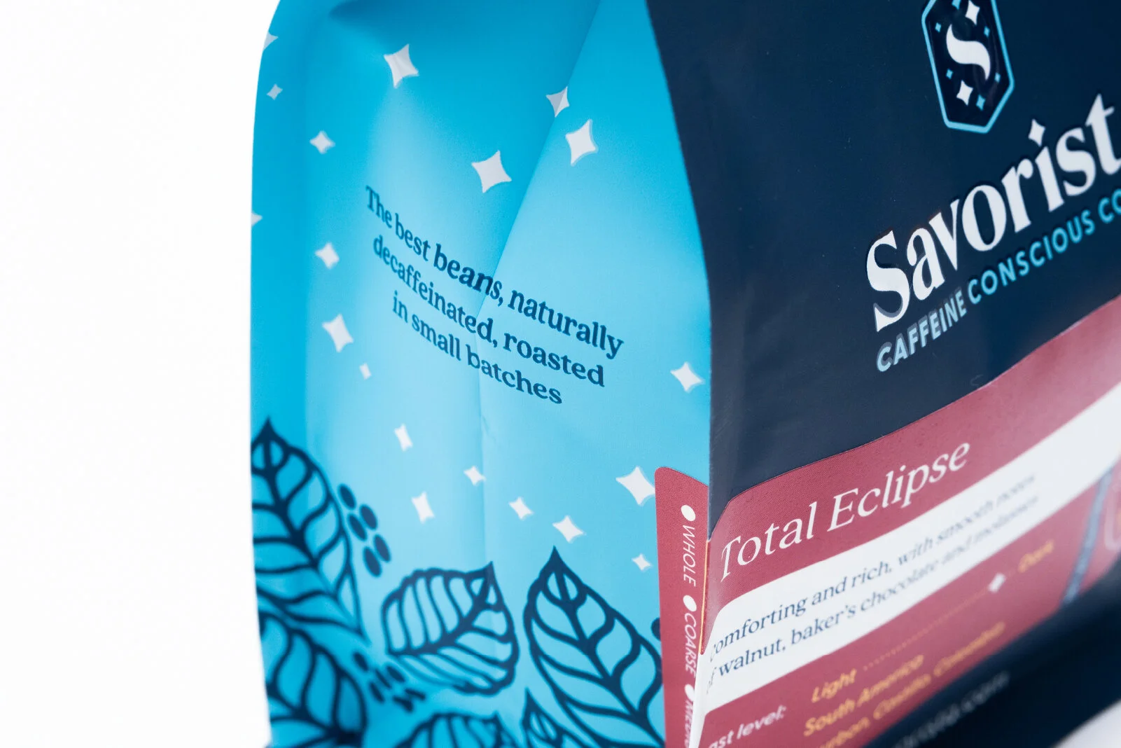 Close-up of a coffee packaging bag with blue and pink colors, featuring text about coffee beans, a leaf illustration, and flavor details.