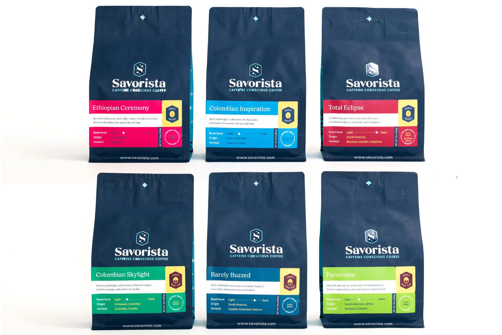 Six packages of Savorista coffee arranged in two rows. The top row has Ethiopian Ceremony, Colombian Inspiration, and Total Eclipse. The bottom row has Colombian Skylight, Barely Buzzed, and Panorama. Each package has a dark blue background with colo