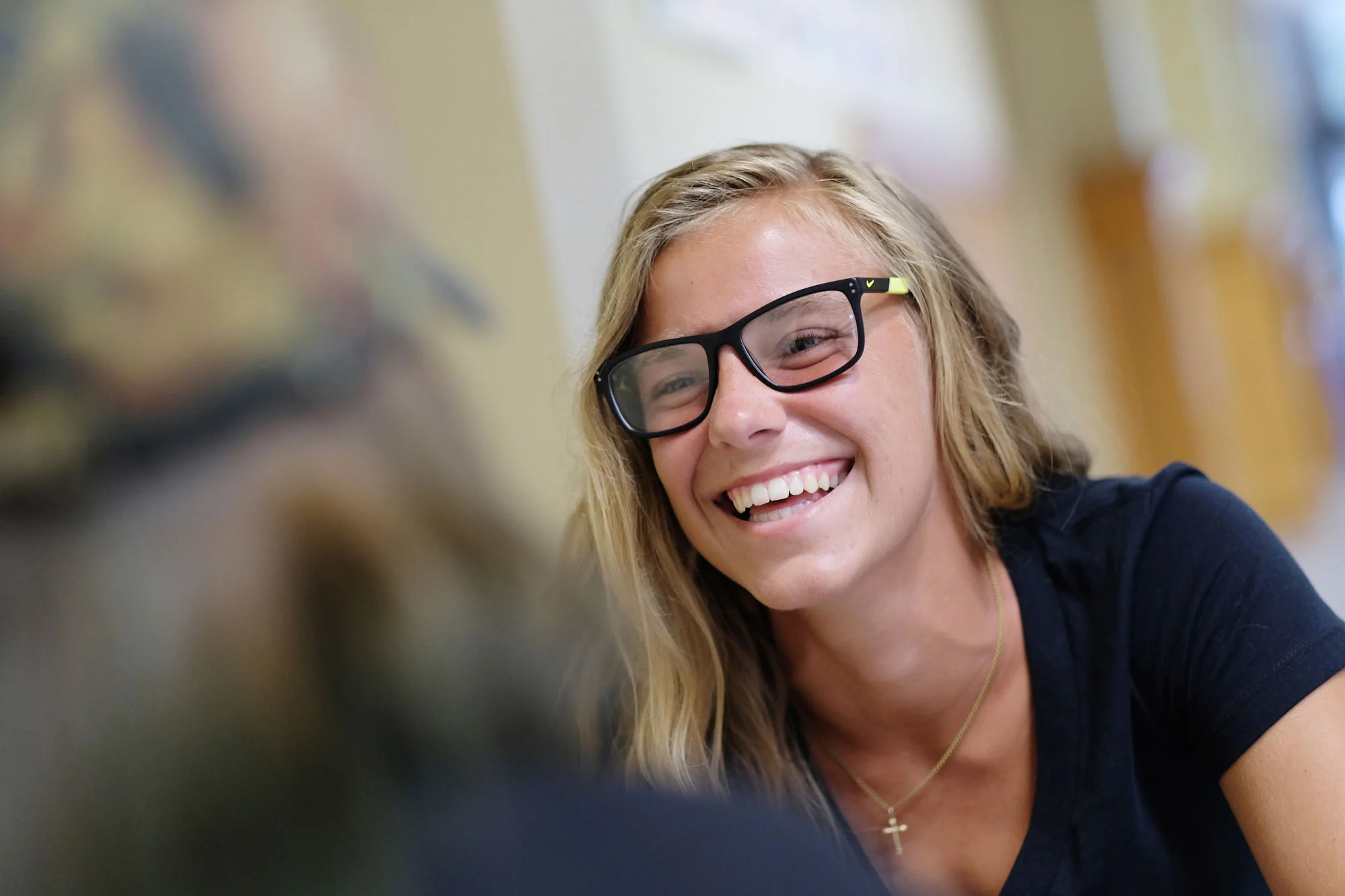 A young woman with blonde hair and glasses smiling.