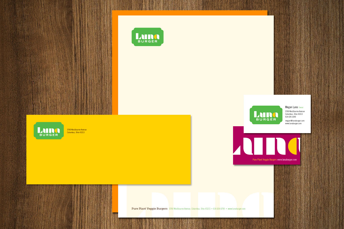 Business branding materials for Luna Burger, including a sheet, business card, and envelope, on a wooden surface.