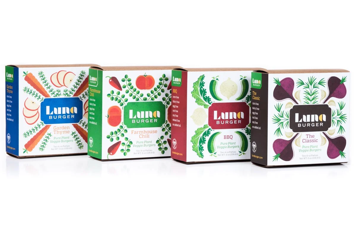 Four boxes of Luna Burger veggie burger patties with colorful vegetable cartoon illustrations on each package.