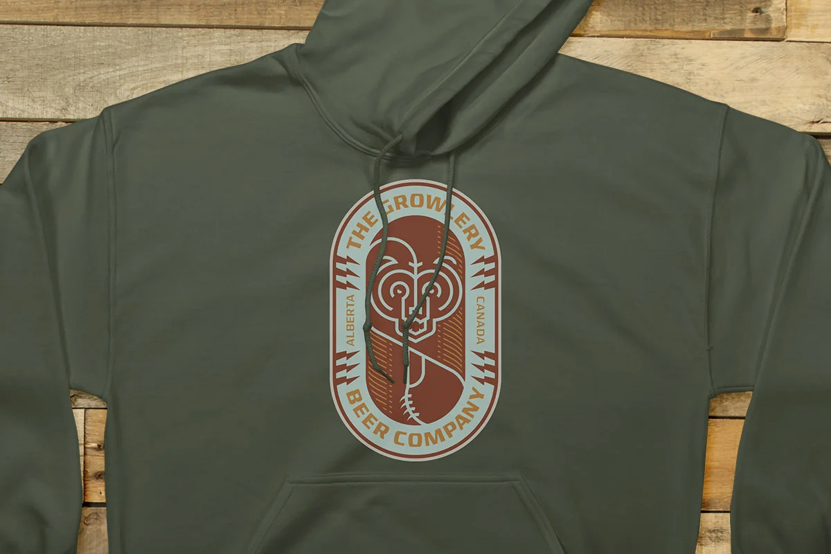 Green hoodie with a logo for The Growler Beer Company in Alberta, Canada, featuring a stylized growler with a face, glasses, and a straw, on a wooden background.