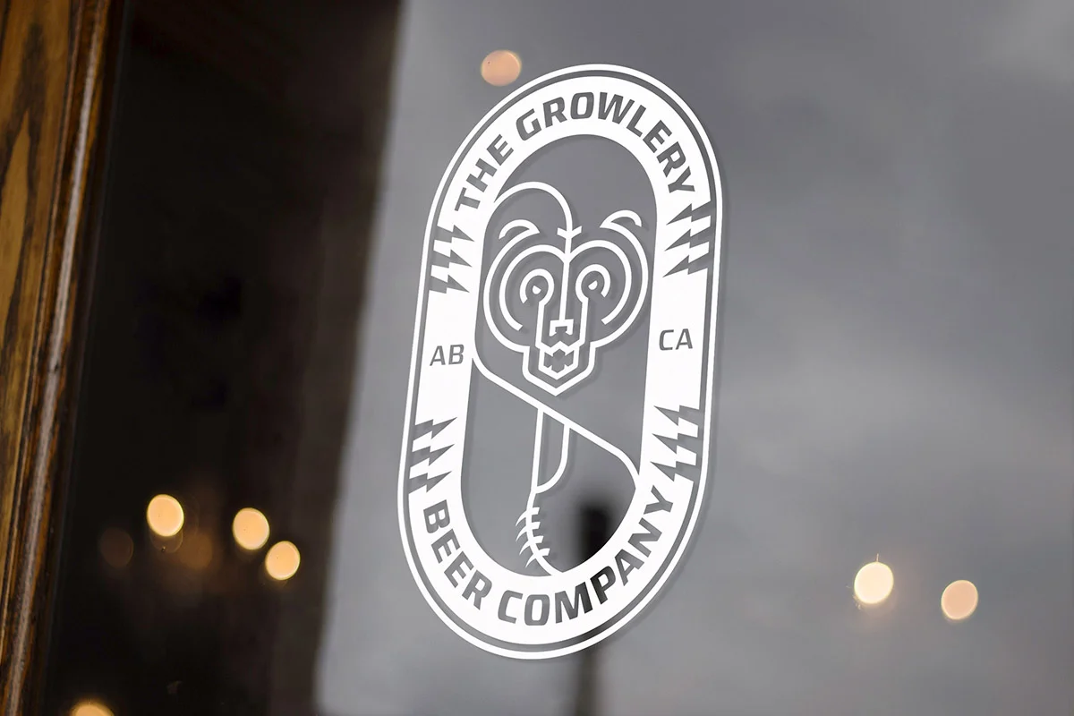 Logo of The Growlery Beer Company on a glass window with a bear face and a hop cone, with the text 'The Growlery Beer Company' and 'AB CA'.
