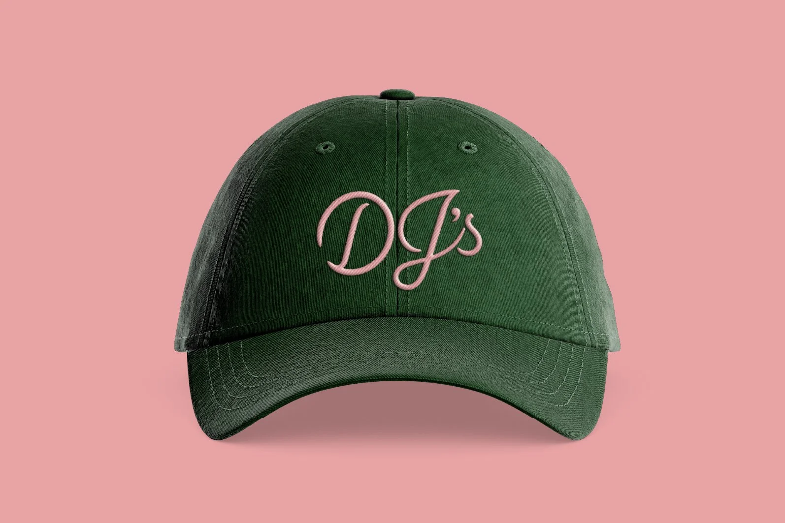 Green baseball cap with pink embroidered text 'DJ's' on the front, set against a light pink background.