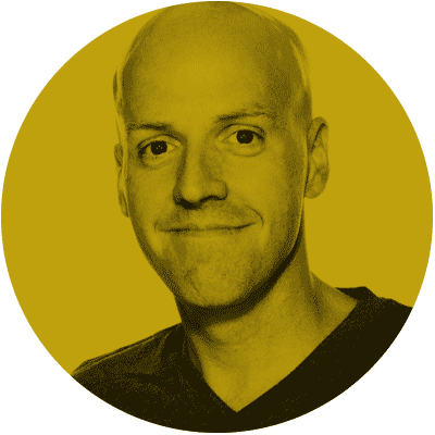 Portrait of a smiling man with a shaved head, wearing a dark shirt, against a yellow circular background.