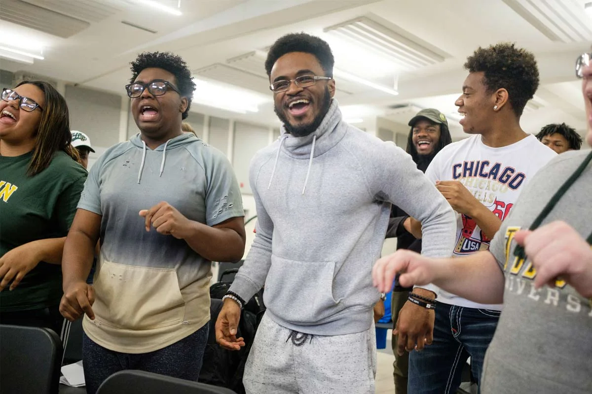 A group of young adults laughing and enjoying themselves indoors at a social gathering.
