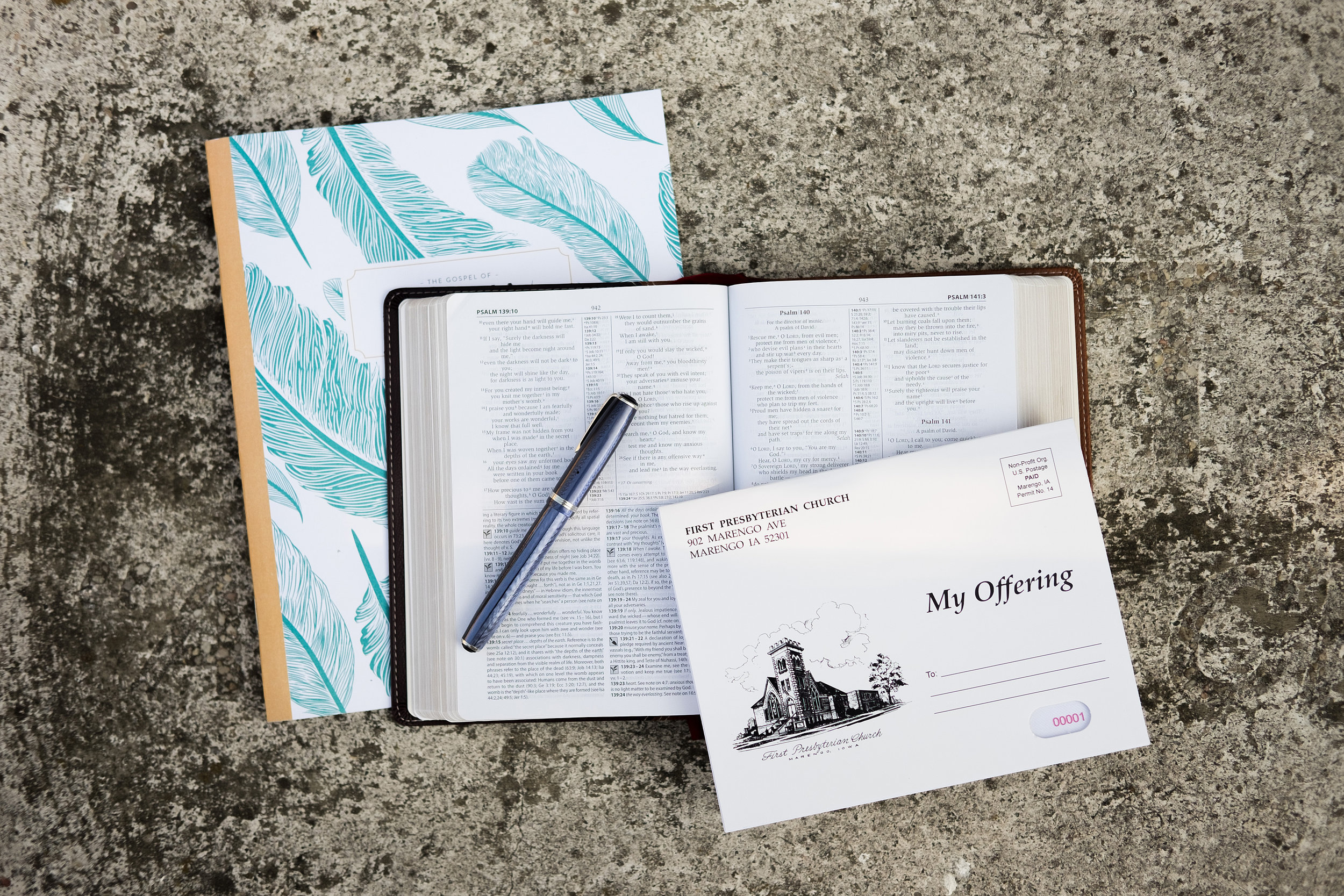 Open Bible, church offering envelope at First Presbyterian Church, pen on Bible, on textured outdoor surface