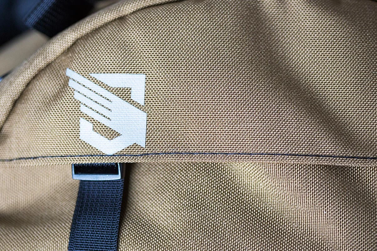 Close-up of a tan backpack with the New York Mets logo in white.