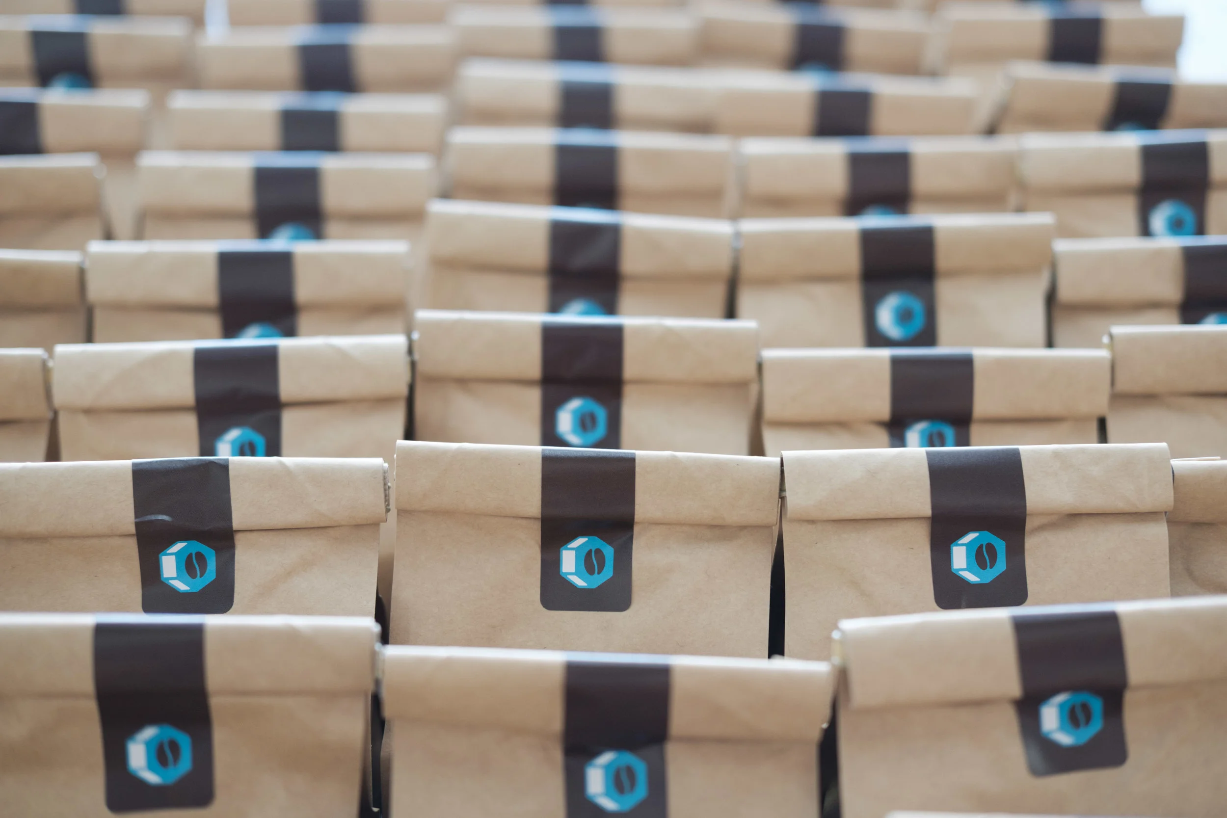 Multiple brown paper bags with black and blue labels arranged in rows, likely in a warehouse or storage area.