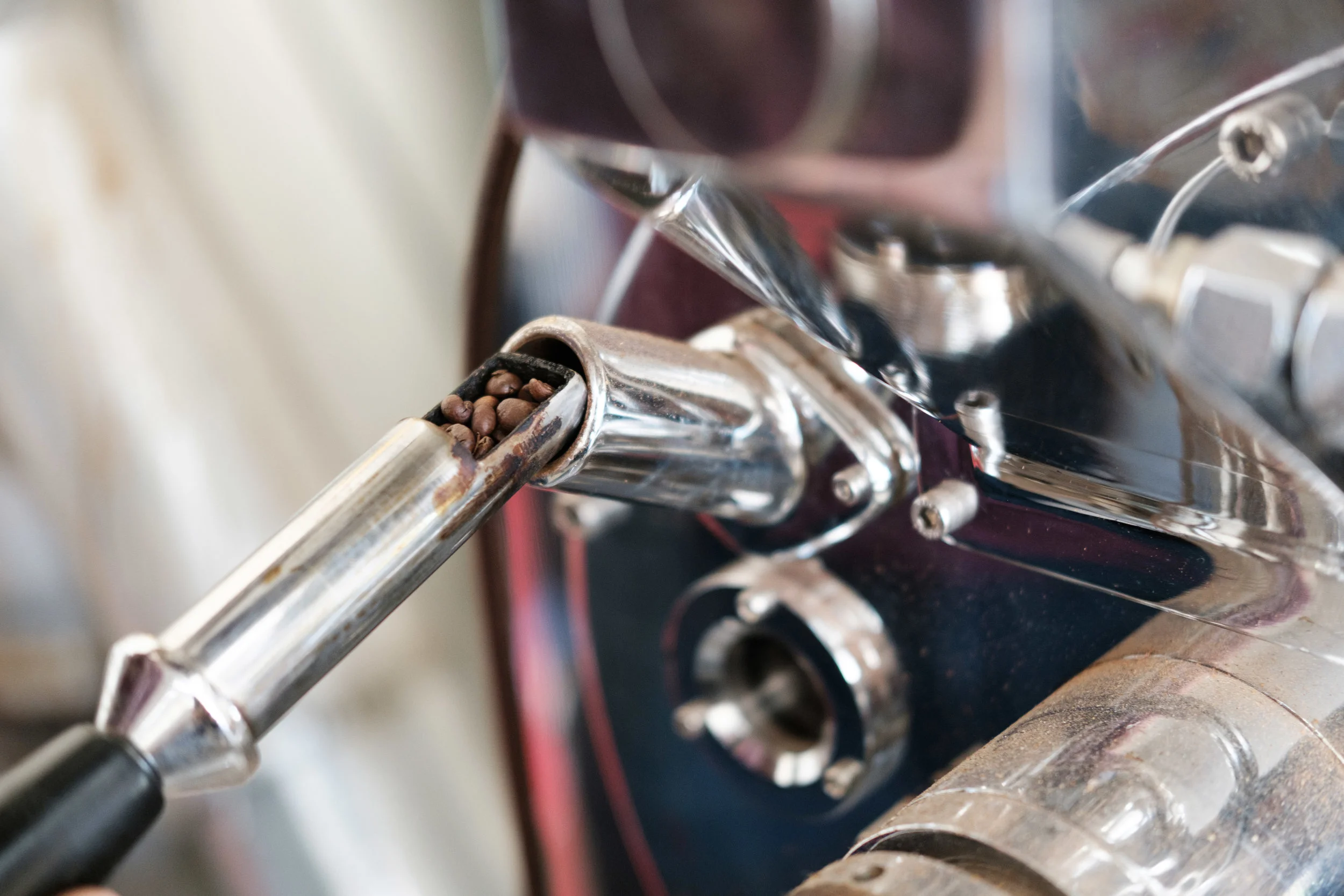 Close-up of a coffee bean hopper in an espresso machine, with some beans visible inside.