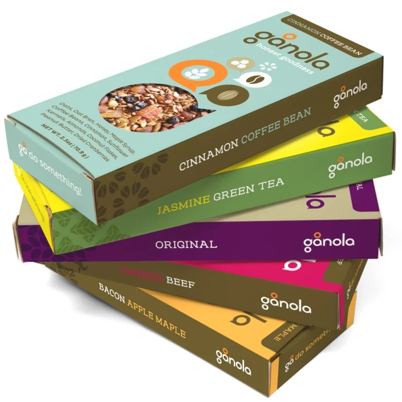 Stack of six tea and coffee boxes from Ganola, including cinnamon coffee bean, jasmine green tea, original, smoked beef, bacon apple maple, and honey apple syrup flavors.