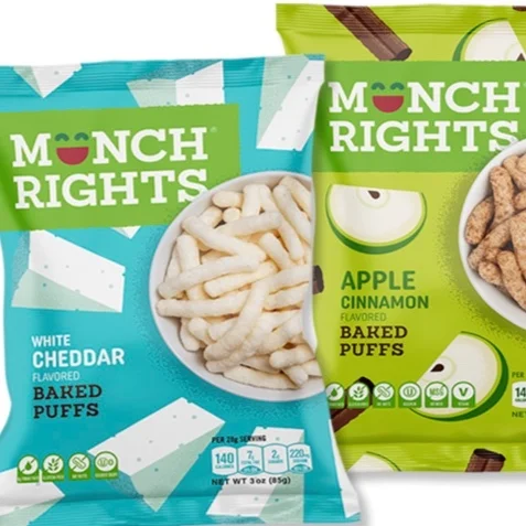 Packages of Monch Rights flavored baked puffs, including white cheddar and apple cinnamon varieties, with some puffs visible inside the packages.