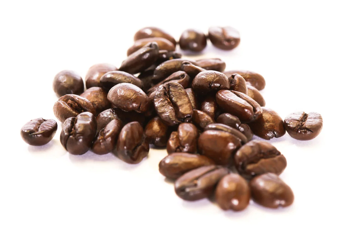 A close-up of roasted coffee beans on a white background