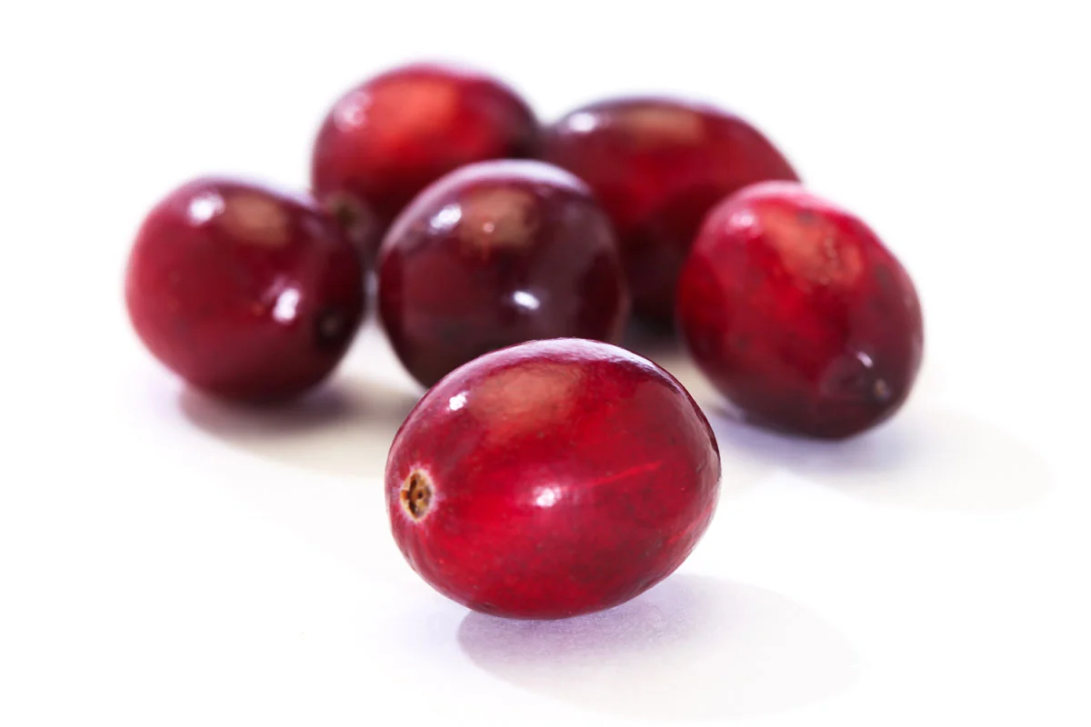 A cluster of six ripe, red cranberries on a white background.