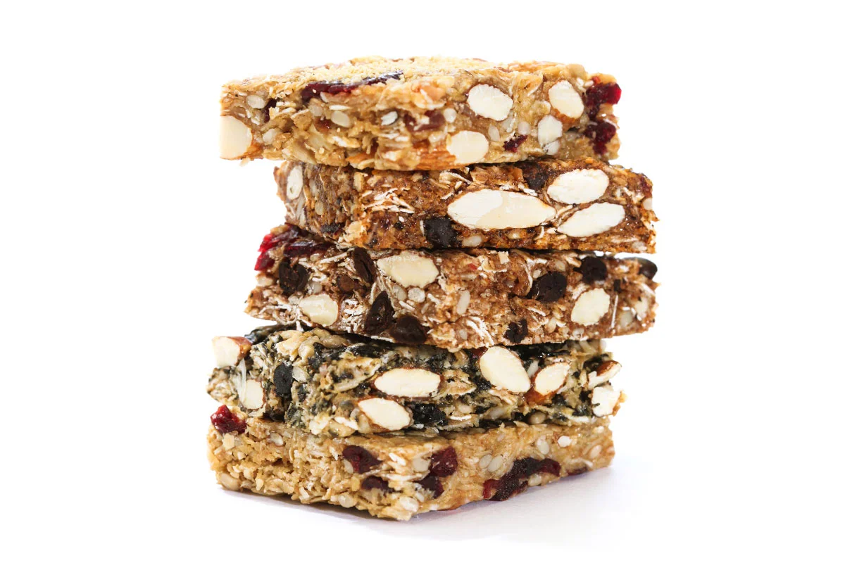 A stack of four granola bars with various nuts, dried berries, and chocolate chips on a white background.