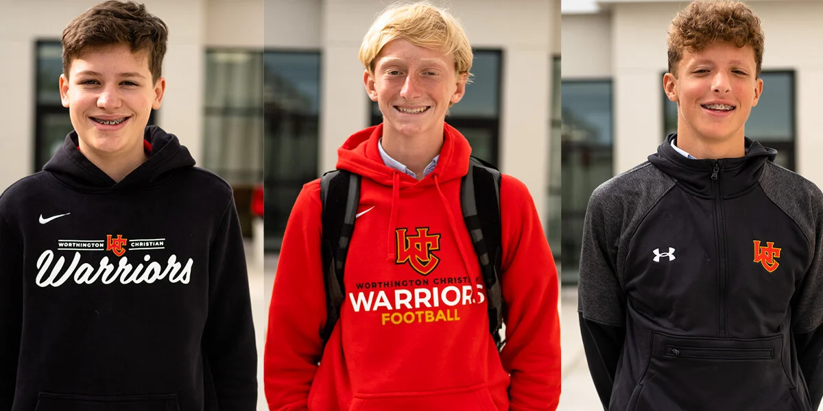 Three teenage boys standing outside, smiling, wearing Worthington Christian Warriors sports hoodies and jackets.