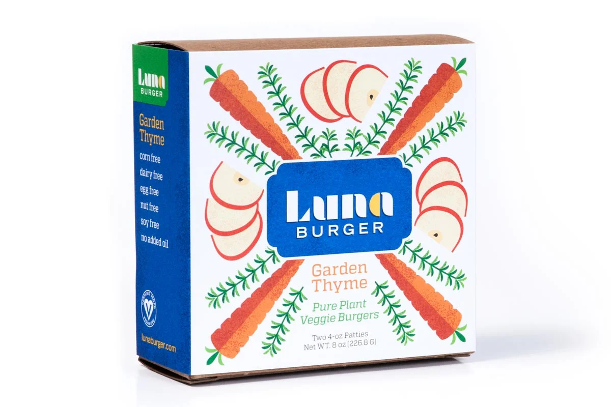 A box of Luna Burger Garden Thyme veggie burgers with illustrations of carrots, radishes, and thyme herbs on the packaging.