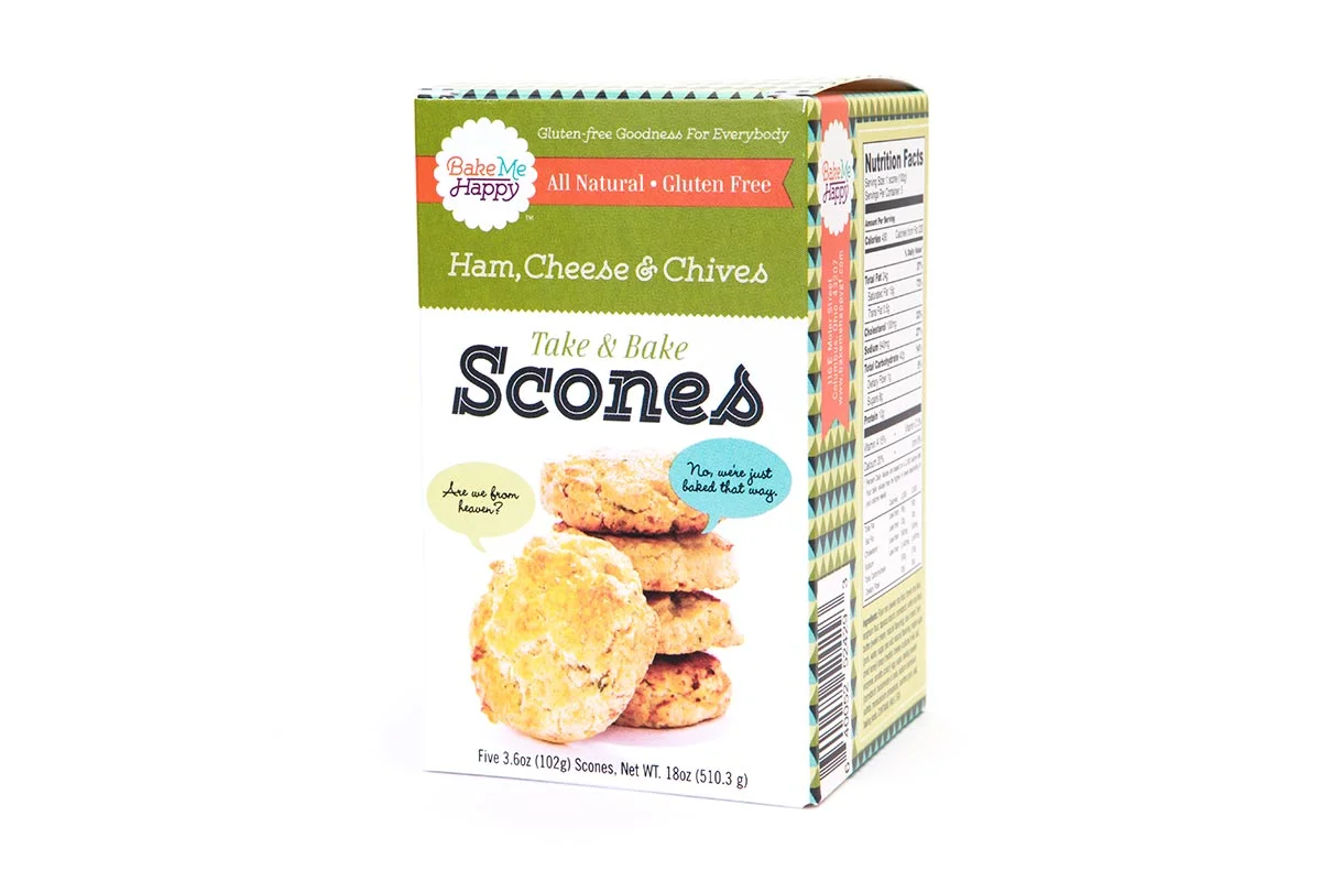 Box of Bake Me Happy ham, cheese, and chives scones with a picture of the scones and playful speech bubbles on the front.