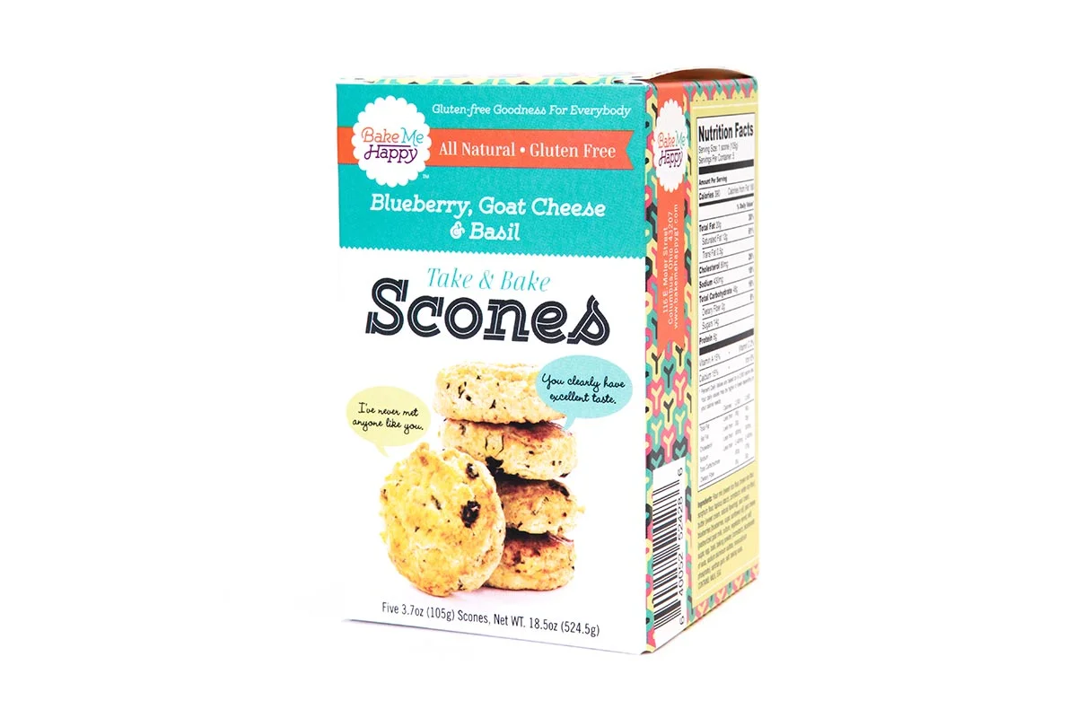 A colorful box of Bake Me Happy blueberry, goat cheese, and basil scones, displaying an image of five scones on the front, with nutritional information on the side.