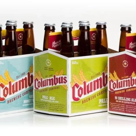 Six bottles of Columbus Brewing Company beer in colorful cardboard carriers.