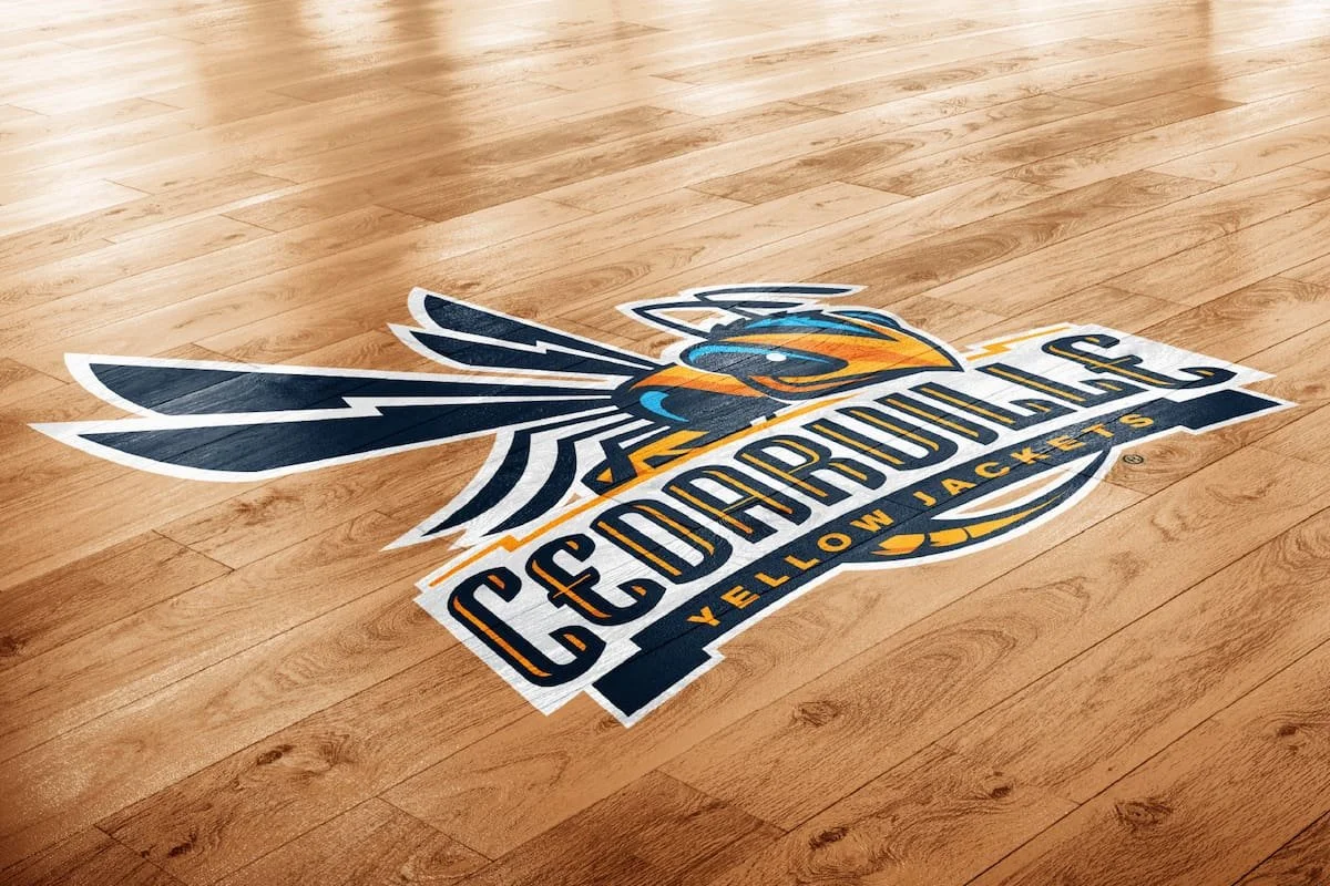 Floor decal with the logo of the Cleveland Charge yellow jackets, a bird with wings, on a wooden floor.