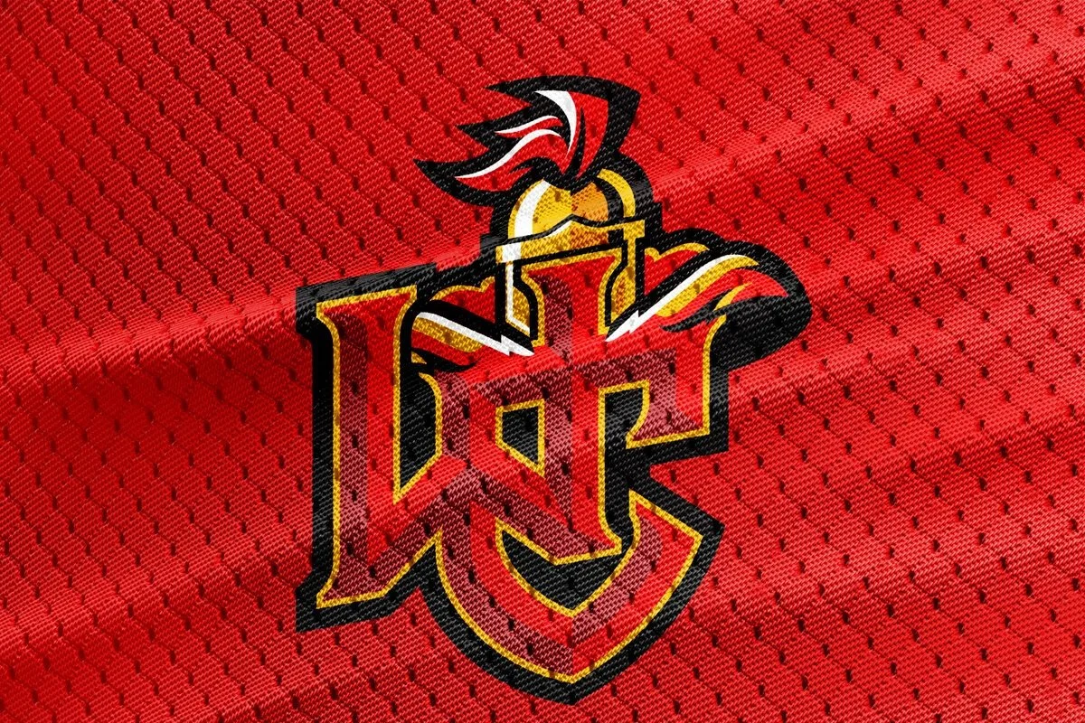Worhngton Christian Warriors logo embroidered on red fabric with small black dots, featuring a stylized letter 'J' with warheilpmetape, outlined in black, red, yellow, and white.