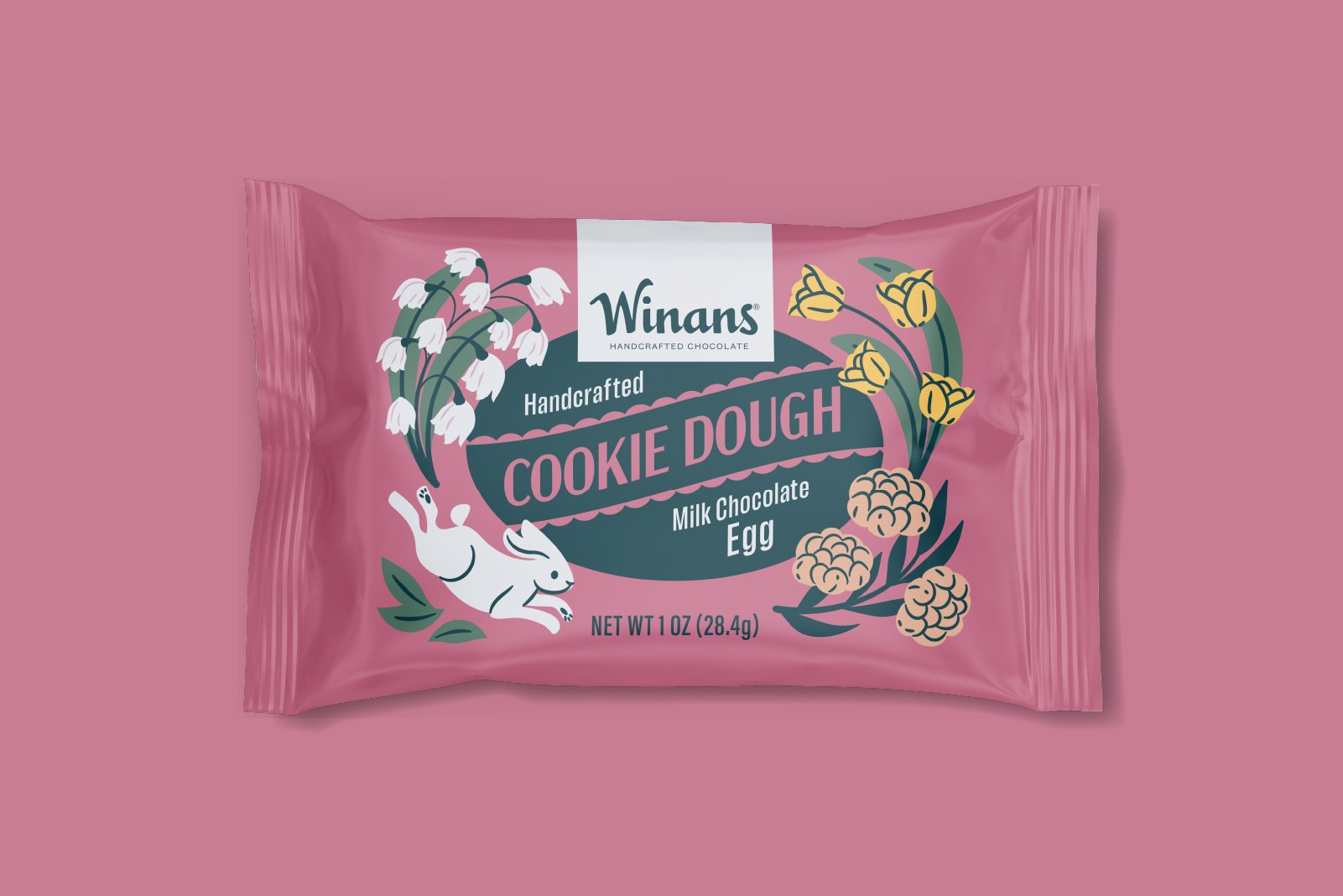 Pink packaging of Winans handcrafted cookie dough milk chocolate egg, decorated with illustrations of white flowers, yellow tulips, and a white rabbit with black eyes and pink nose. Packaging design and illustration by Slagle Design. 