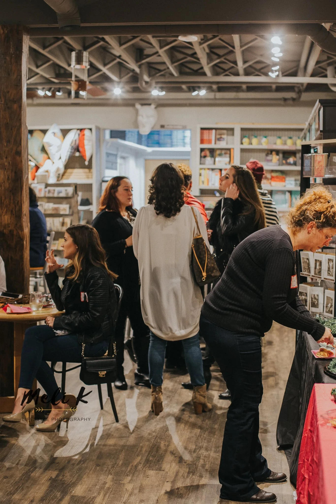 Group of women shopping at an indoor marketplace with shelving and decorative objects in the background.