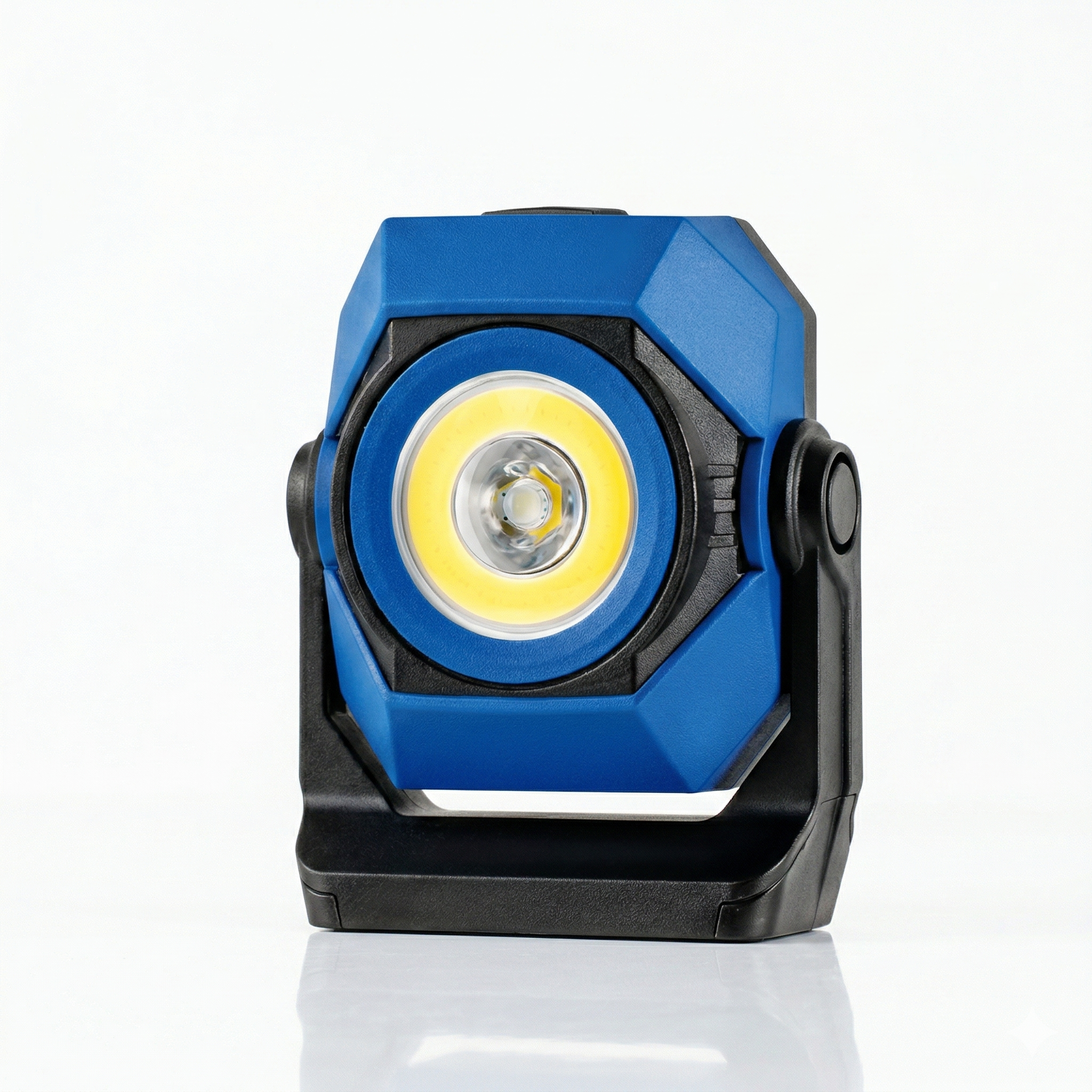 A small, portable LED work light with a blue and black body, turned on with a bright yellow light, on a white surface against a white background.