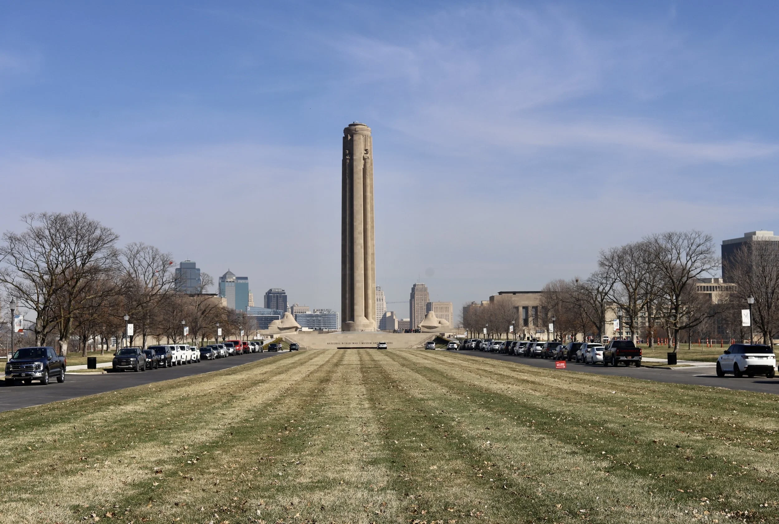 The Gateway Arch dominating the skyline with surrounding trees, grassy area, and parking lots in St. Louis, Missouri.