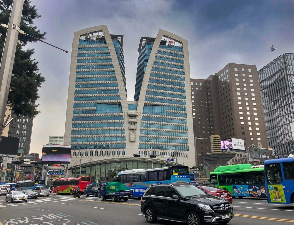 City street scene with modern high-rise buildings, buses, cars, and traffic lights in Seoul, South Korea.