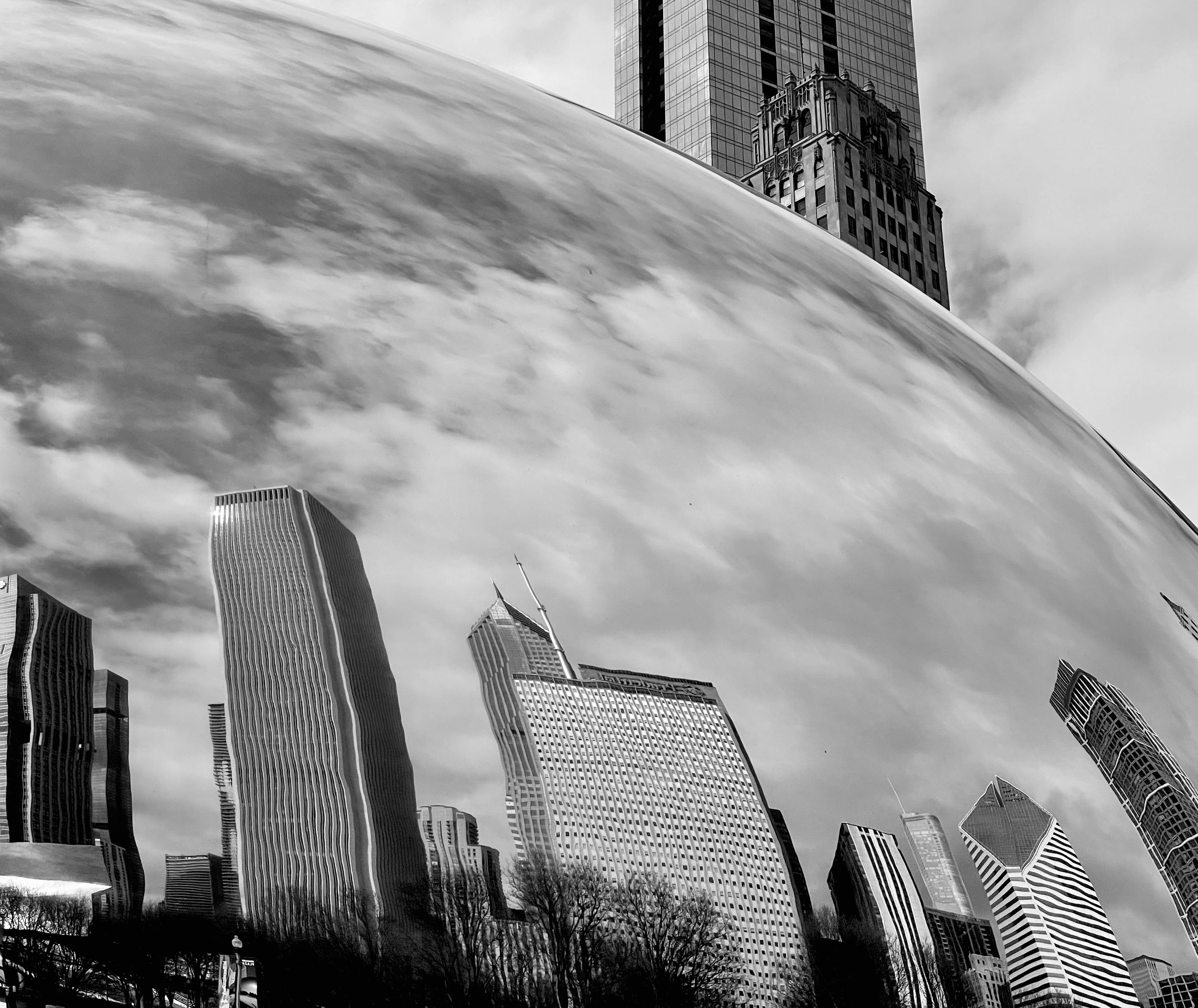 Black and white photo of city skyline with distorted and wavy skyscrapers reflected on a curved, shiny surface.