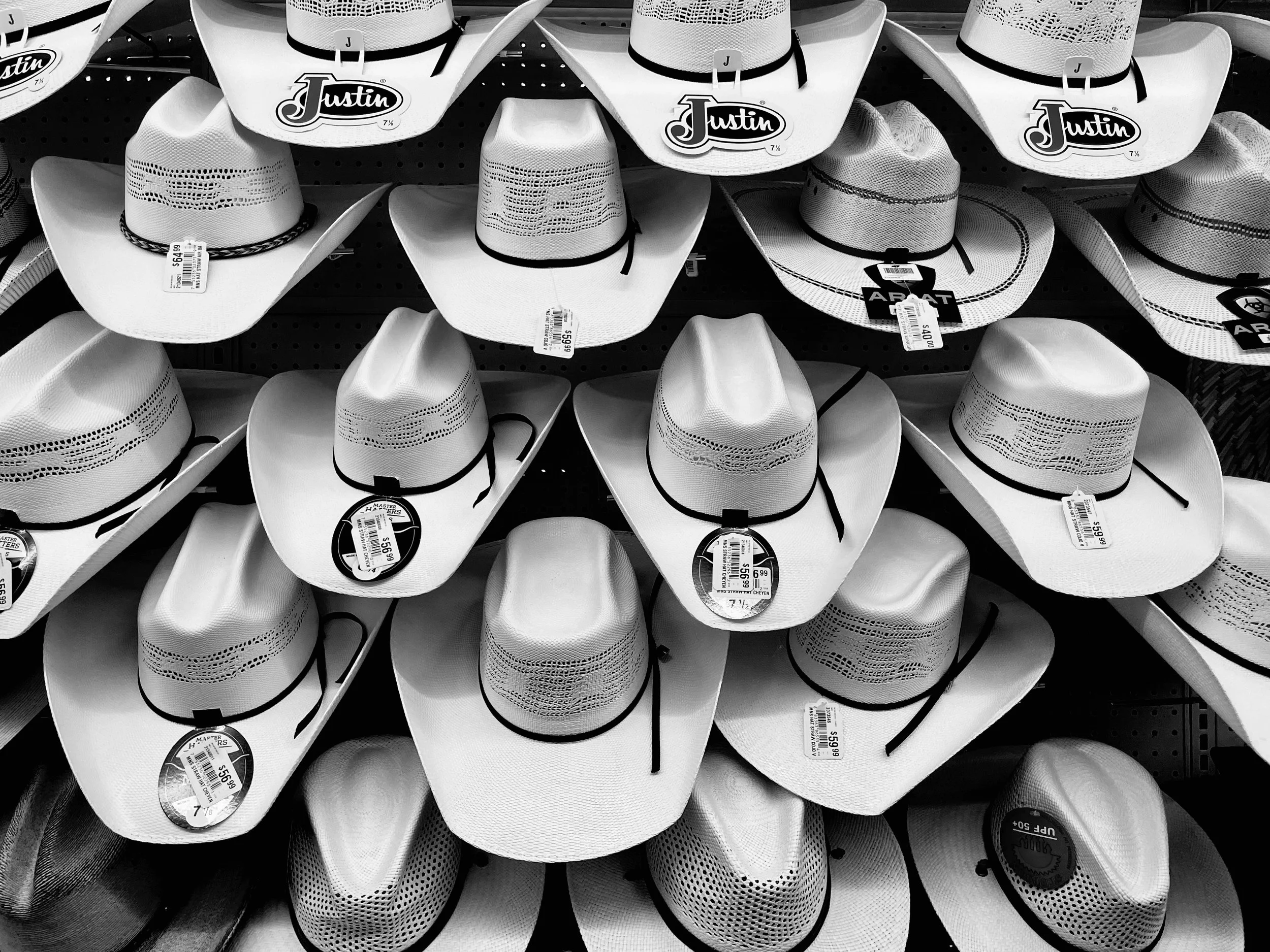A display of white cowboy hats with black bands on a store shelf.