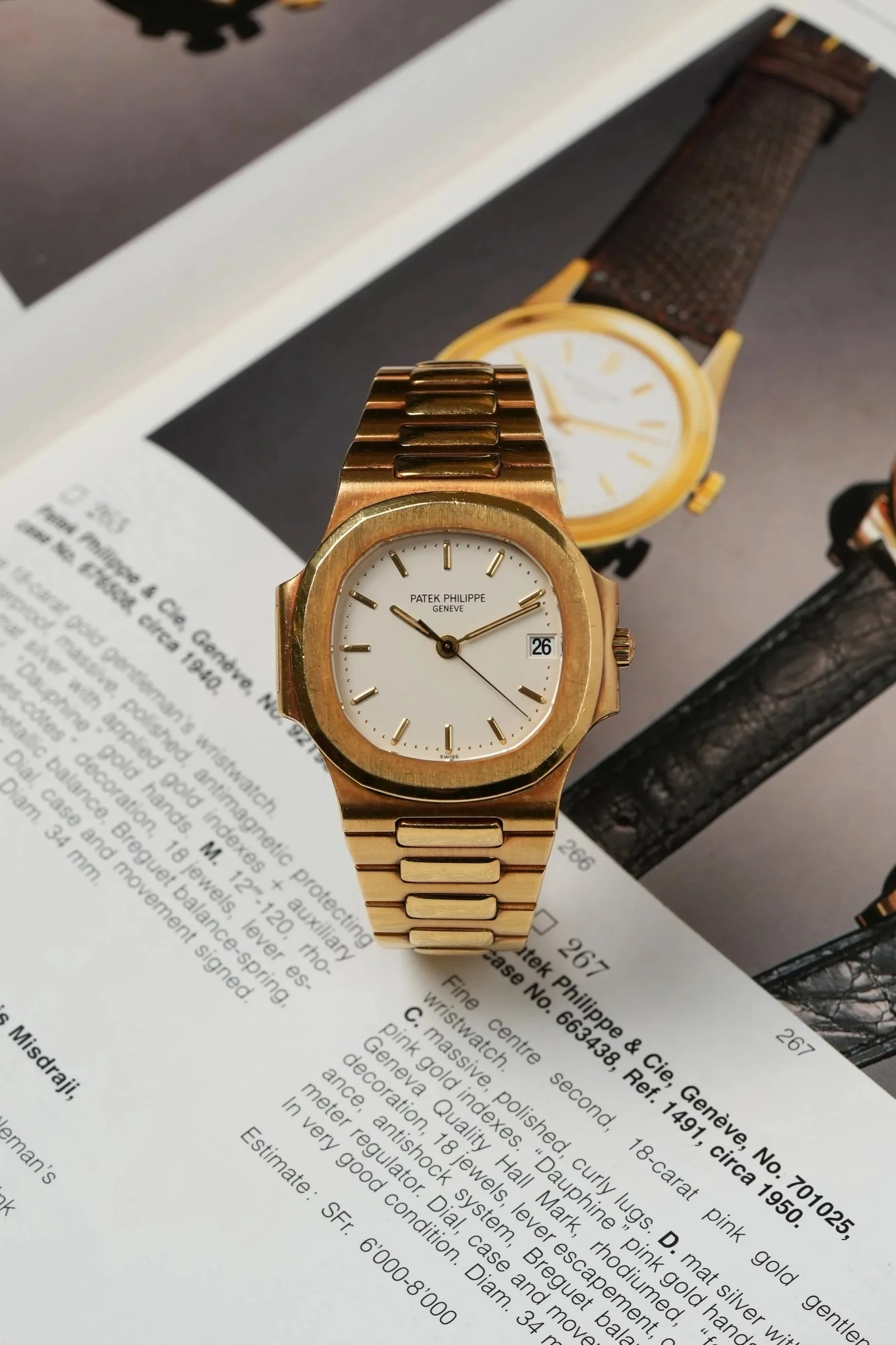 Close-up of a gold Patek Philippe wristwatch with a white dial, gold hour markers, and a date window, placed on a page featuring another watch image and watch description text.