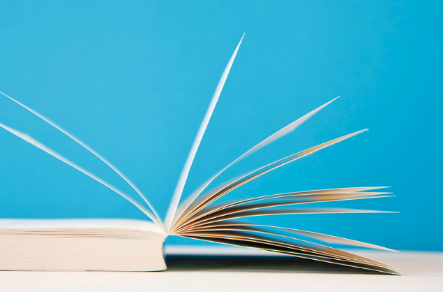 Open book with pages fanned out against a blue background.
