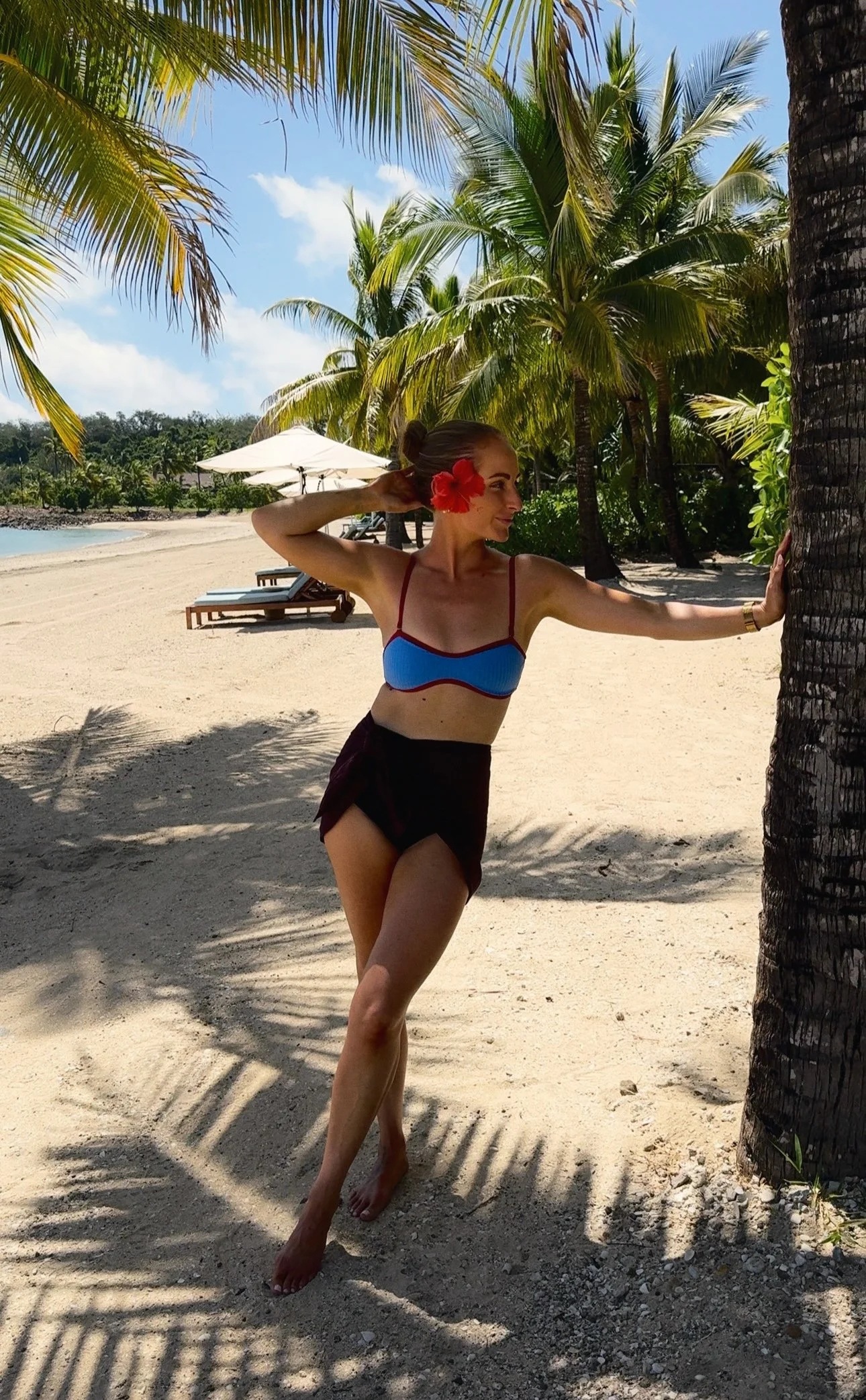 Aimee beneath palm trees beside a tropical beach