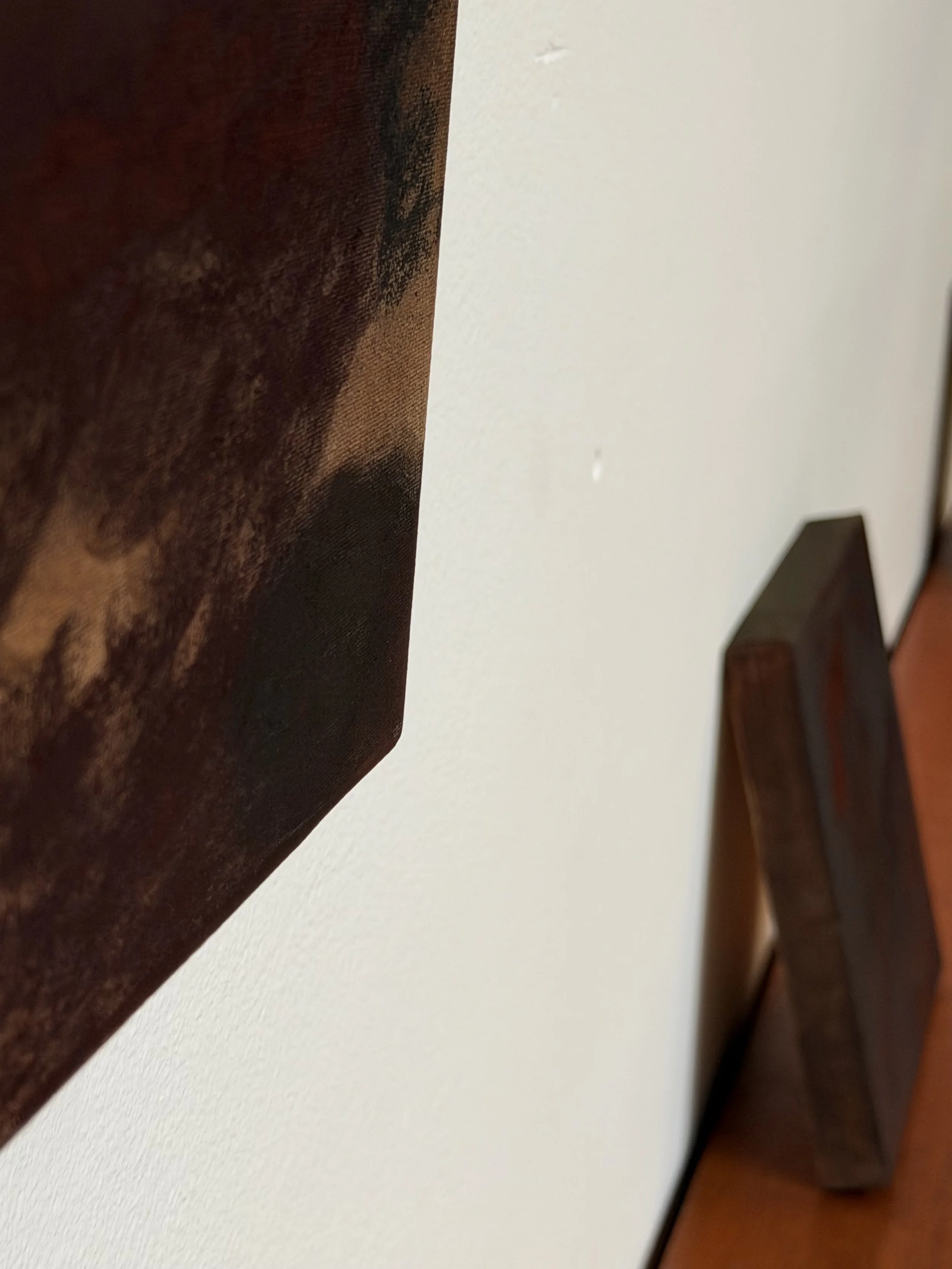 Close-up of a wooden headboard and a white wall with a textured surface.