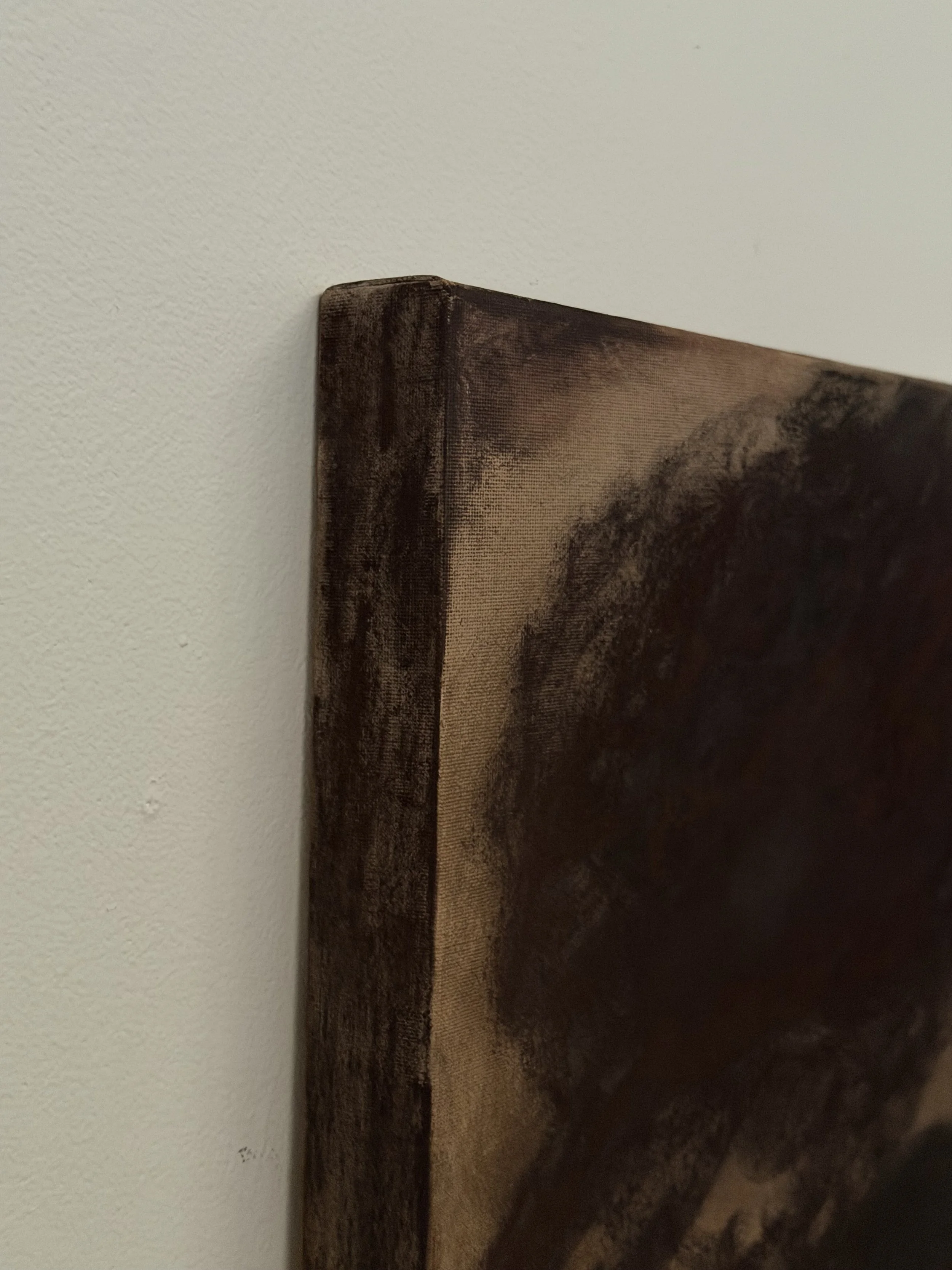 Close-up of a dark brown wooden picture frame corner hanging on a white wall.