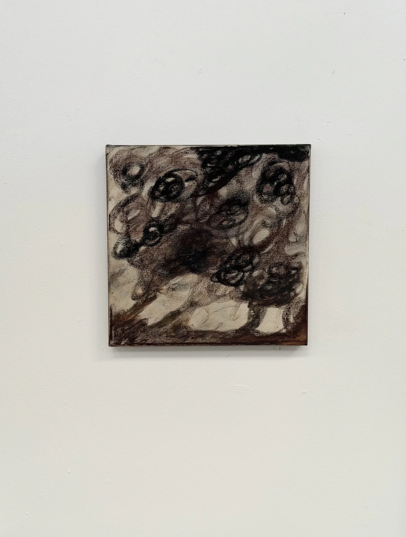 Abstract expressionist painting with dark, swirling shapes on a textured canvas, hung on a plain white wall.