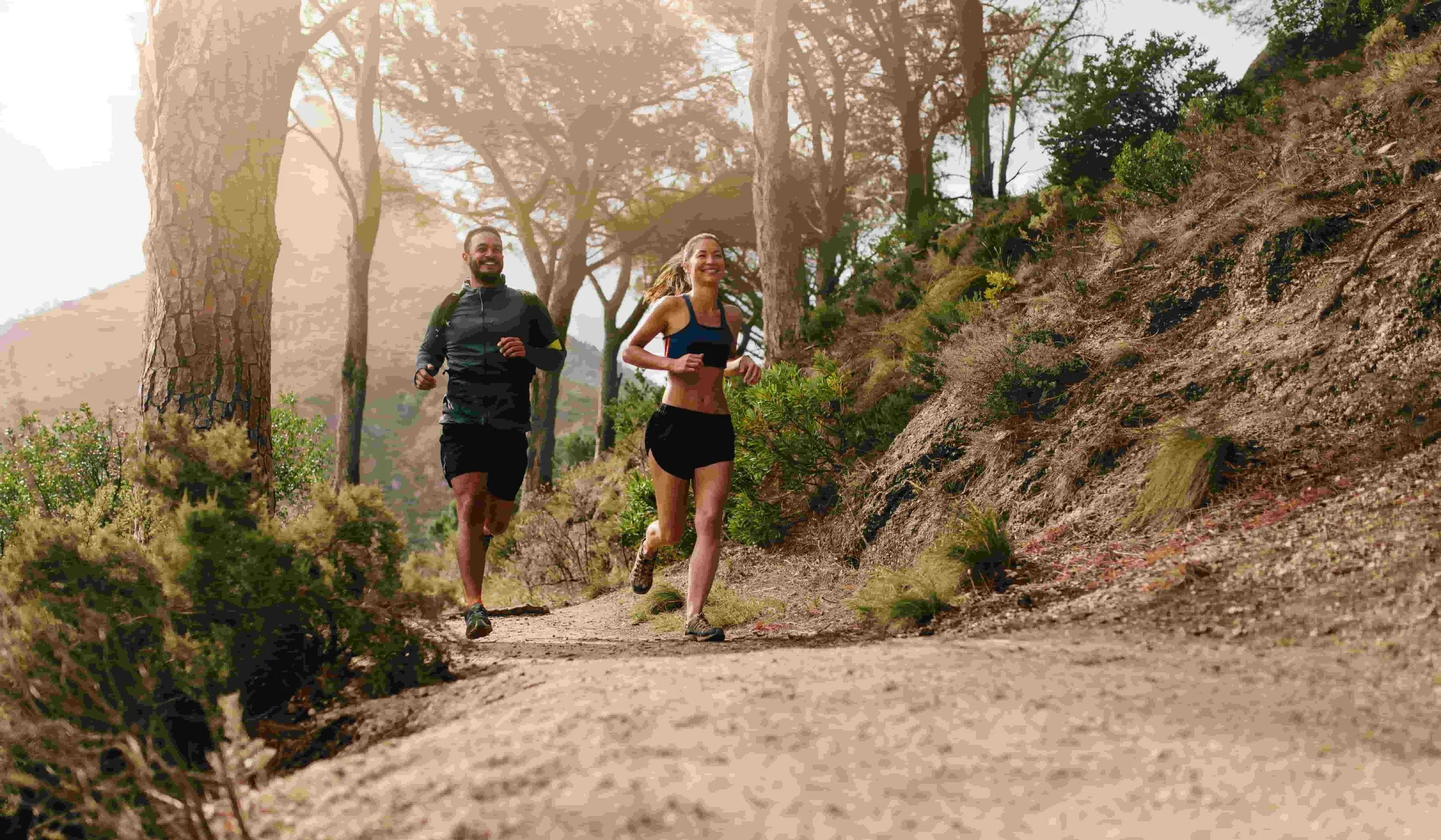 A group of endurnace athletes running through a wooded trail together.