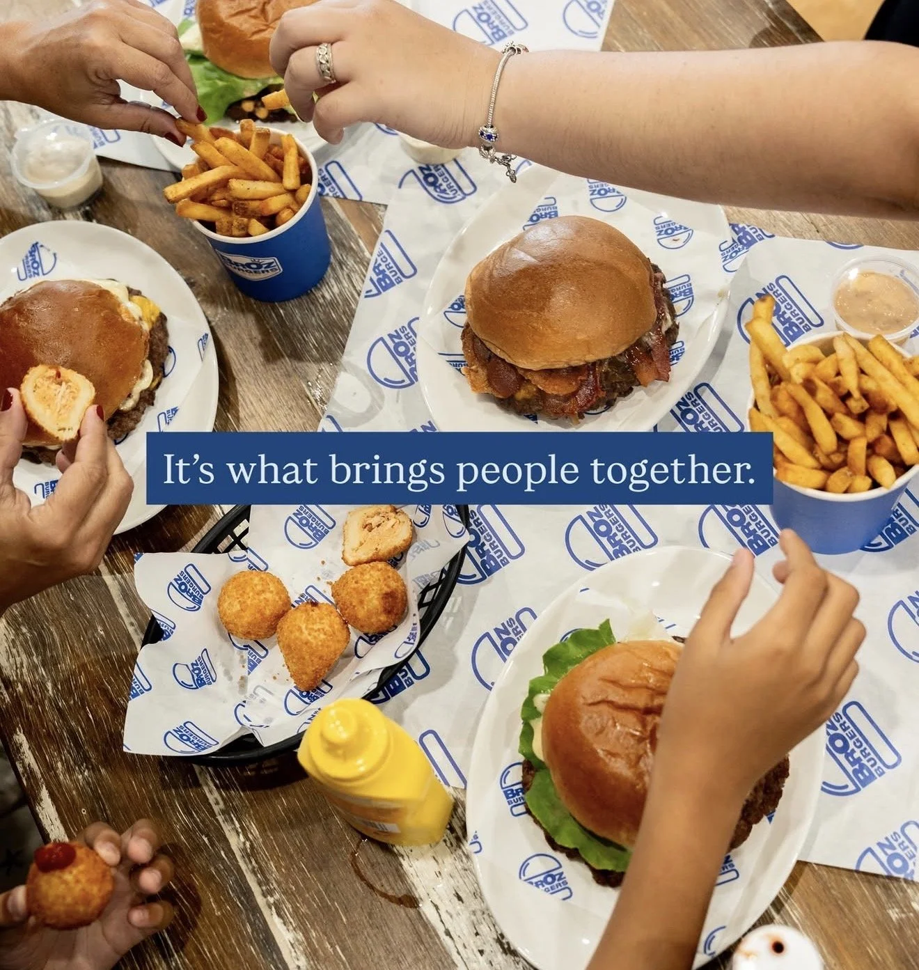 Burgers and loaded fries served at BrOz Burgers Sydney, with crispy chips and dipping sauce on branded table.